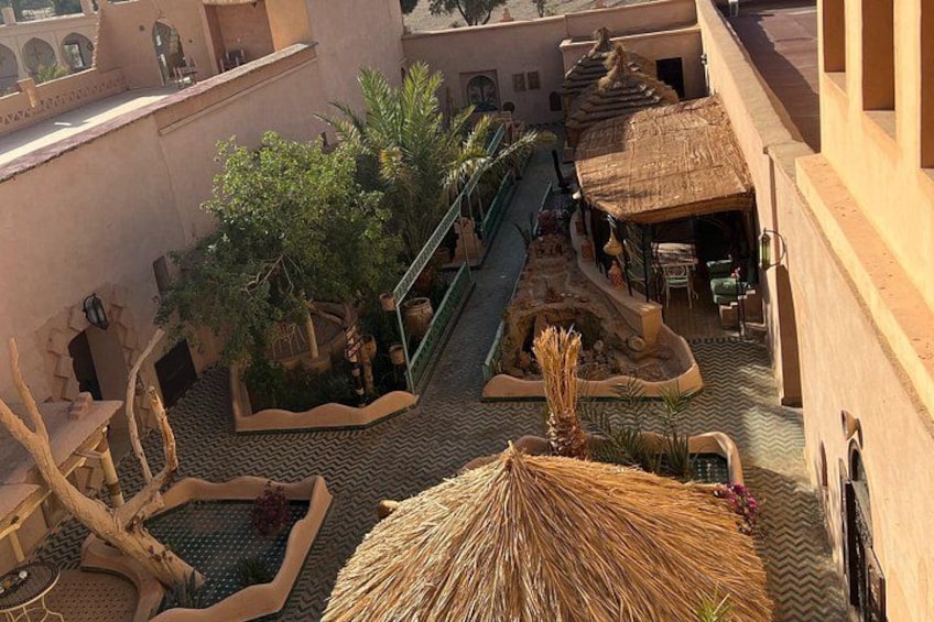 A courtyard with a palm tree, a thatched roof structure, and a staircase. 2