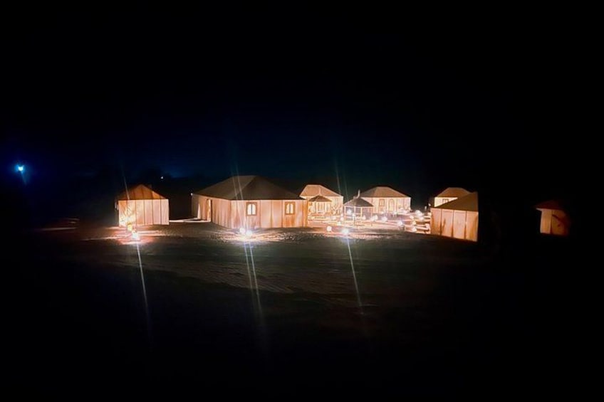 A series of illuminated yurts at night. 3