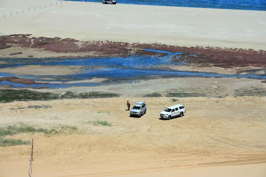 A desert landscape with two vehicles and a person standing. 2