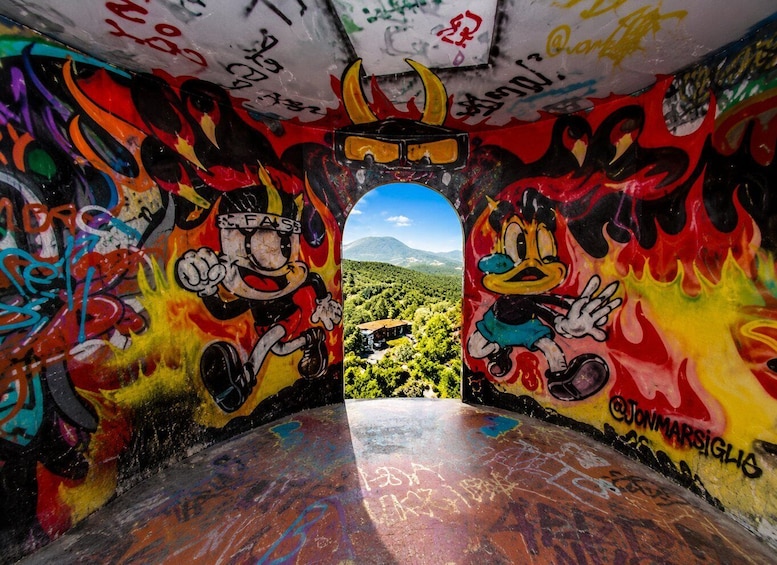 An indoor graffiti tunnel with vibrant murals of cartoon characters and flames, leading to a scenic outdoor view. 4