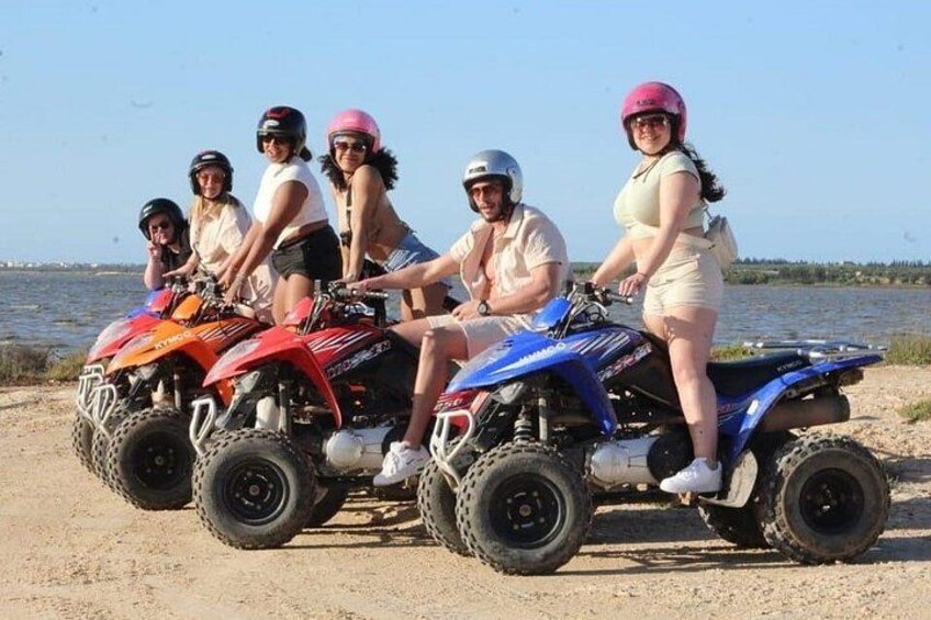 Un grupo de personas manejando cuatrimotos junto a un lago. 1