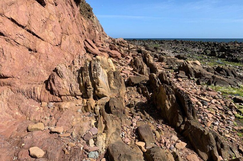 Un paisaje costero rocoso con formaciones rocosas estratificadas y cielo despejado. 5