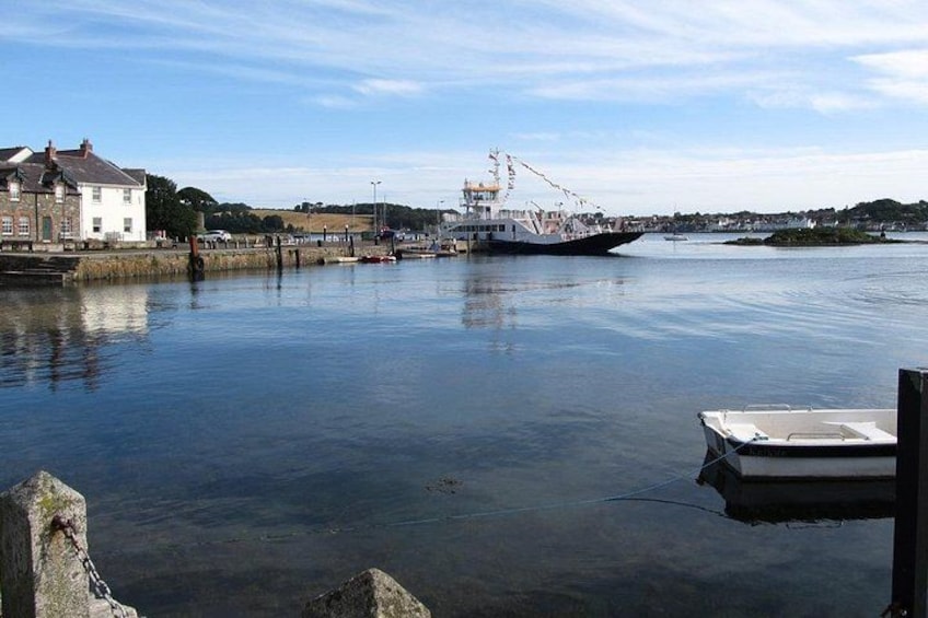 Un puerto tranquilo con un barco grande amarrado, una lancha cerca del muelle y edificios a lo largo de la costa. 5