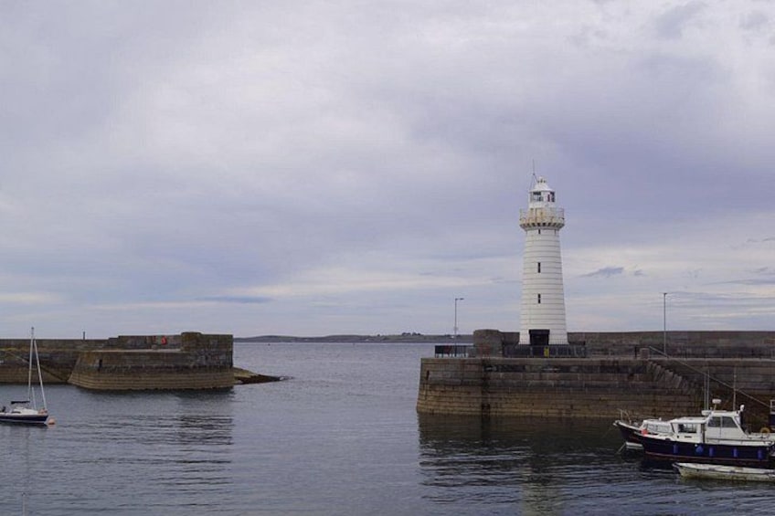 Un faro, un barco y un rompeolas rocoso en el agua. 1