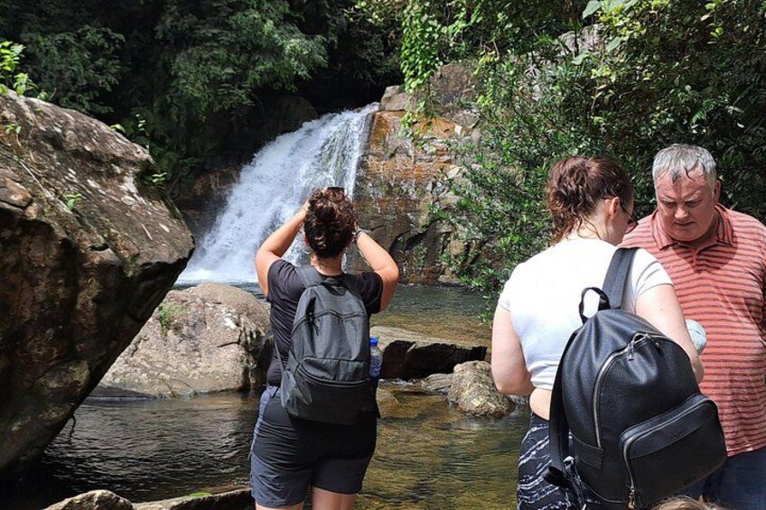 A waterfall, a rocky terrain, and people observing the scene. 1