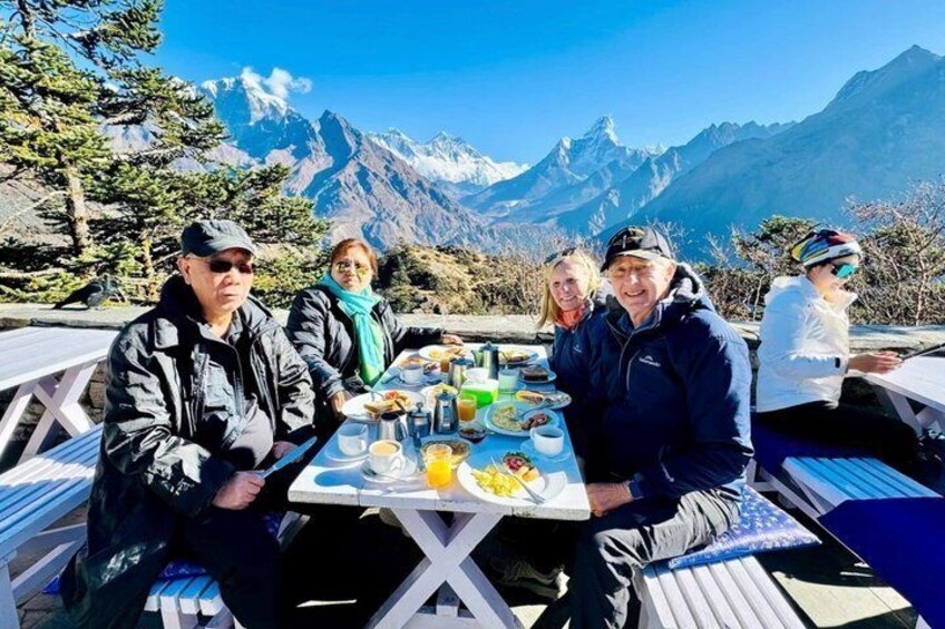 Eine Gruppe von Menschen speist an einem Tisch mit Blick auf eine Berglandschaft. 1