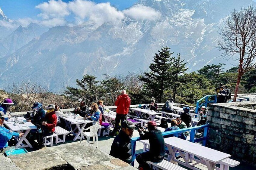 People dining at tables with a mountain backdrop. 4