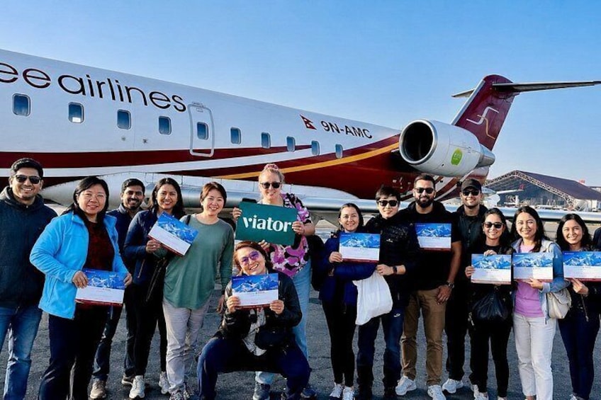 Un gruppo di persone in piedi di fronte a un aereo con la scritta 'ee airlines' e '9N-AMC'. 1