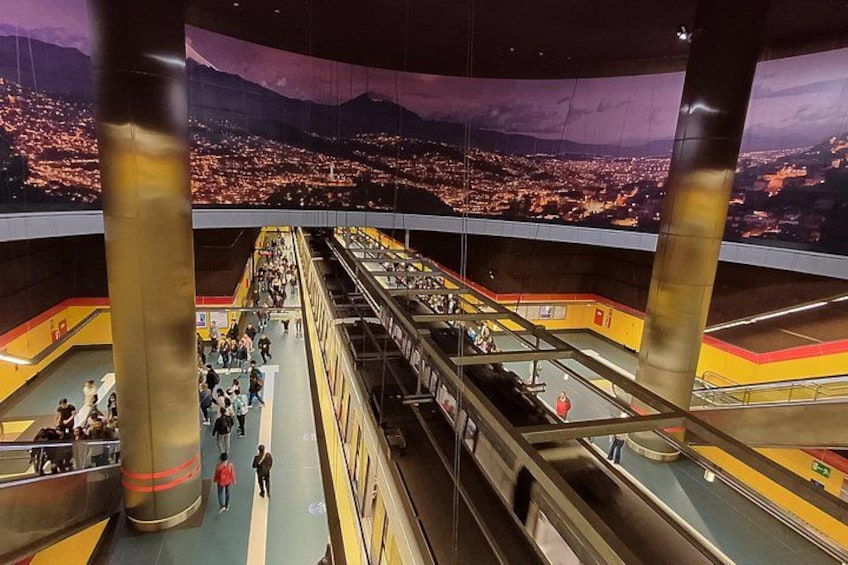 Une gare avec de nombreuses voies et une grande fresque représentant un paysage urbain. 1