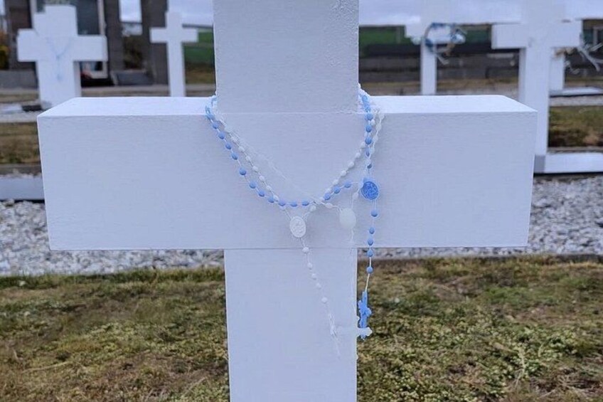 A white cross with a blue and white beaded necklace. 3