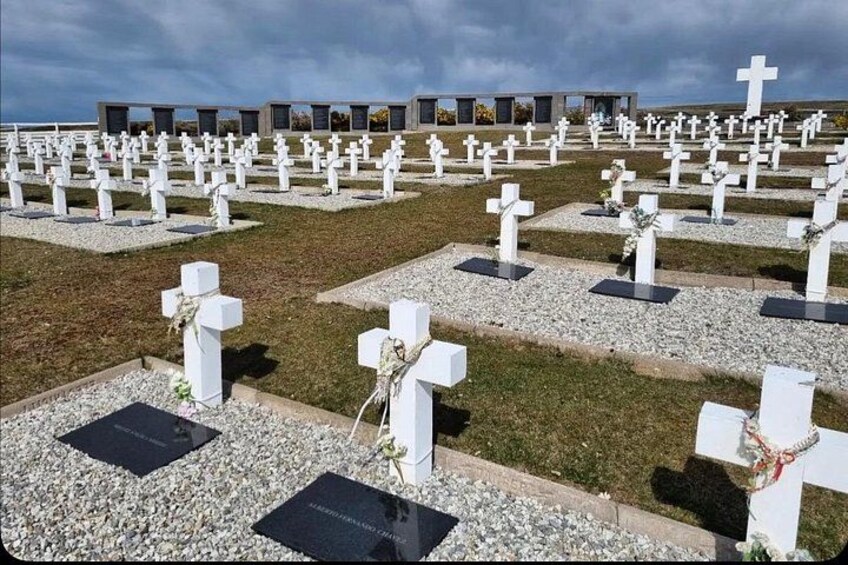 A cemetery with numerous white crosses and headstones. 2