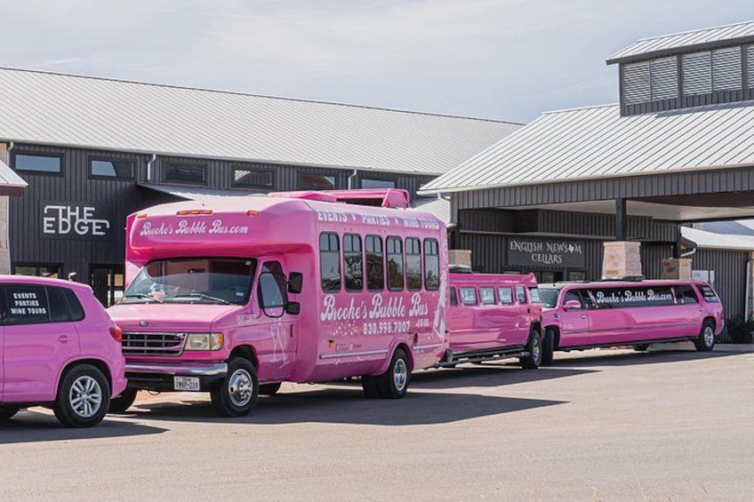 A pink food truck parked in front of a building with signage. 2