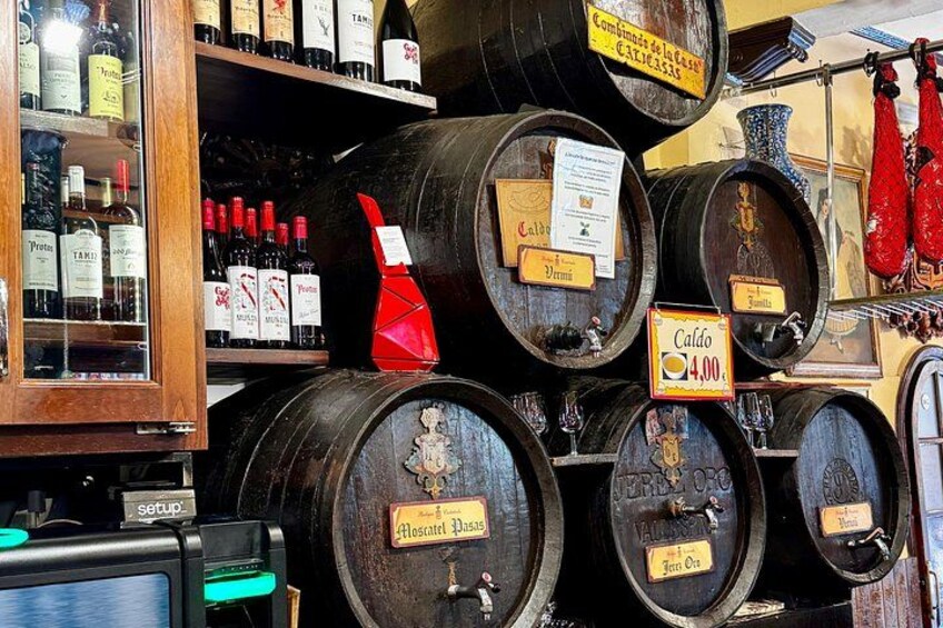 A wine cellar with wooden barrels, a red wine bottle, and a price sign. 3