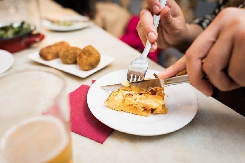 Una persona cortando una rebanada de pastel con un tenedor y un cuchillo sobre un plato blanco. 2