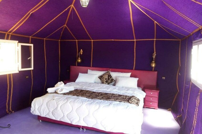 A tent-style bedroom with a bed, pillows, and a nightstand. 2