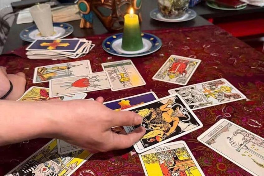 Una persona disponiendo cartas de tarot sobre una mesa con una vela y elementos decorativos. 1