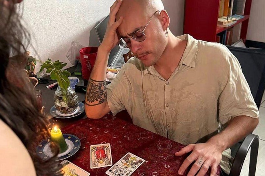 Una persona sentada a una mesa con cartas de tarot y una vela. 2