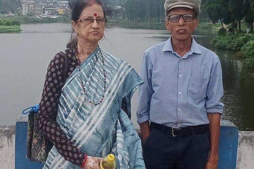 Two people standing by a river with a bridge in the background. 5