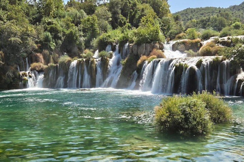Une cascade se jetant dans une rivière aux eaux claires, le tout entouré d’une végétation luxuriante. 4