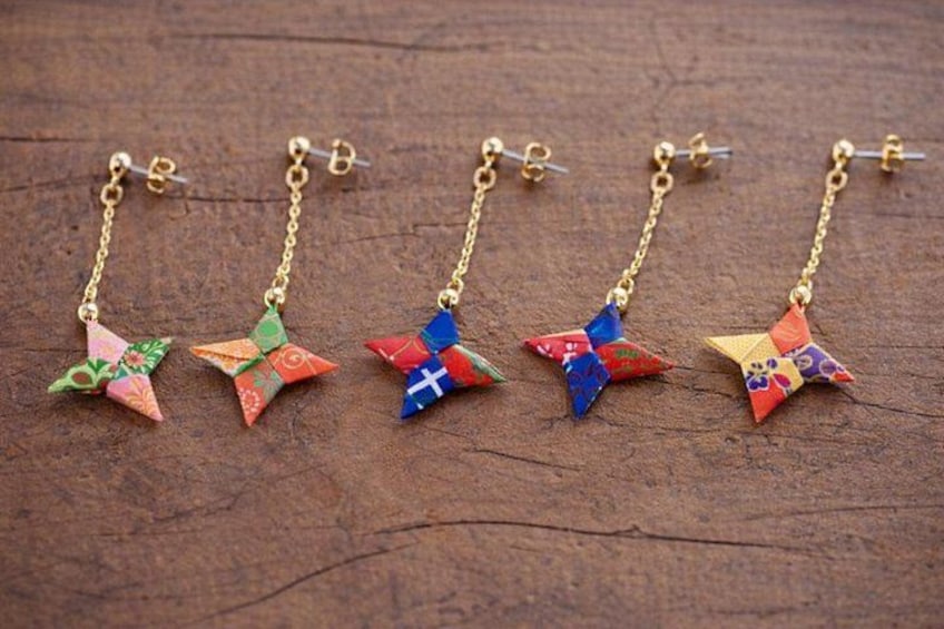 Five pairs of earrings with colorful star-shaped pendants on gold chains. 4