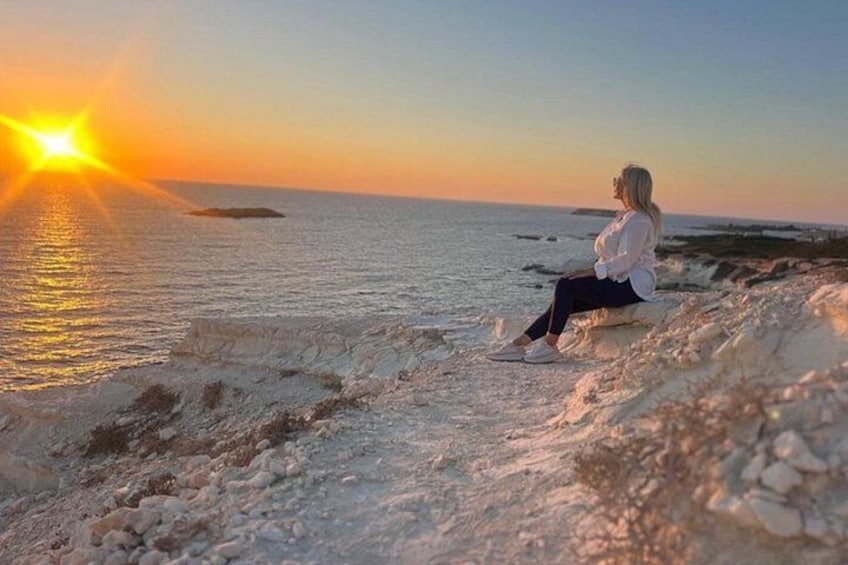 En person sidder på en stenet strand i solnedgangen. 1