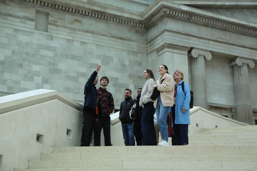 A group of people standing on a staircase in front of a building with classical architecture. 1