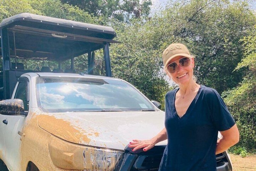 A person standing next to a vehicle with a covered cargo area, surrounded by greenery. 4