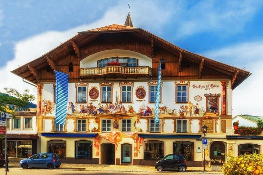 Un edificio bávaro tradicional con decoraciones elaboradas y una bandera azul y blanca a rayas. 1
