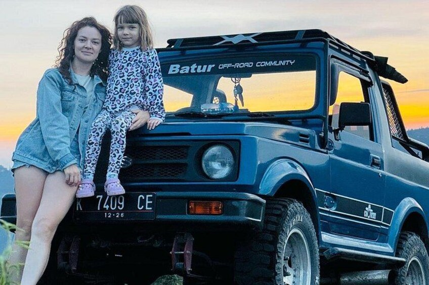 Un vehículo todoterreno azul con una placa de matrícula y una persona sentada en el capó. 2