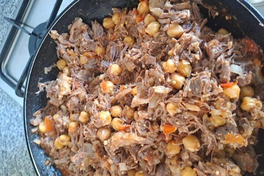 A pan filled with shredded meat and chickpeas. 1