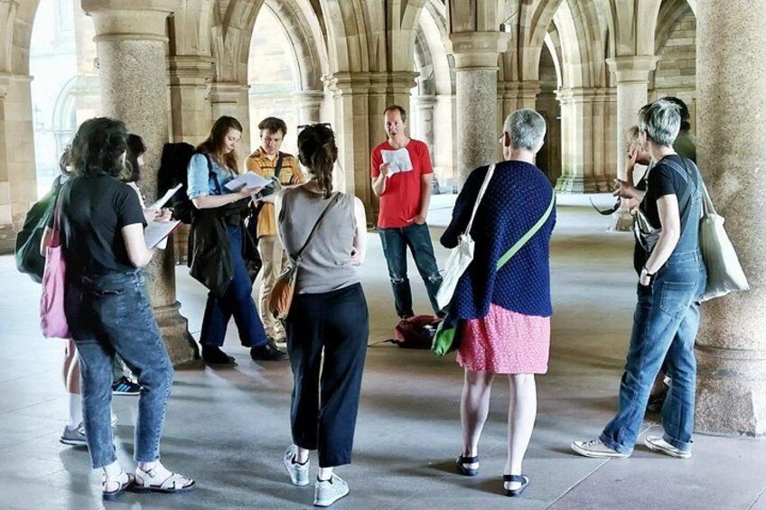 Eine Gruppe von Menschen steht in einem historischen Gebäude mit Bögen und Säulen. 2