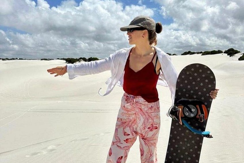 A person standing on a sandy beach holding a snowboard. 4