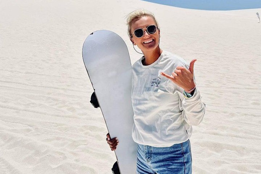 A person holding a snowboard on a sandy beach. 3