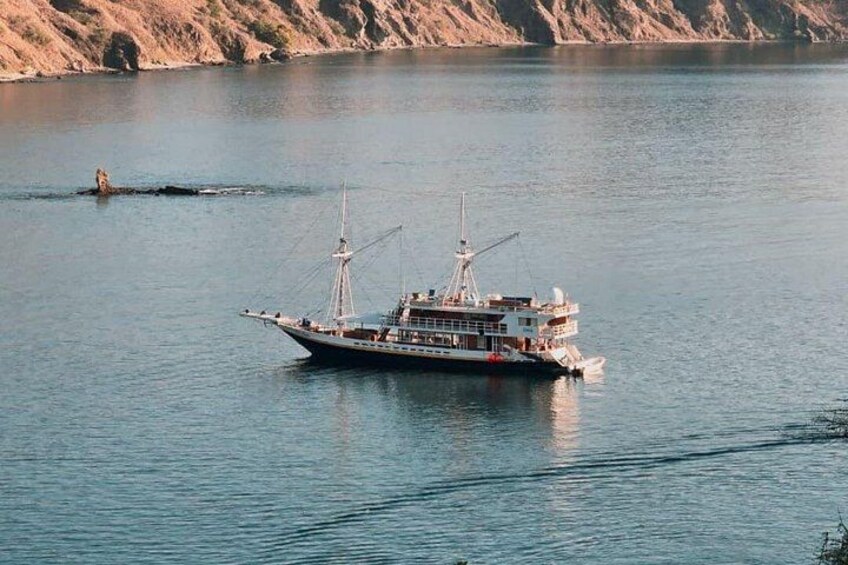 En båd på stille vand med en klippefyldt kystlinje i baggrunden. 3