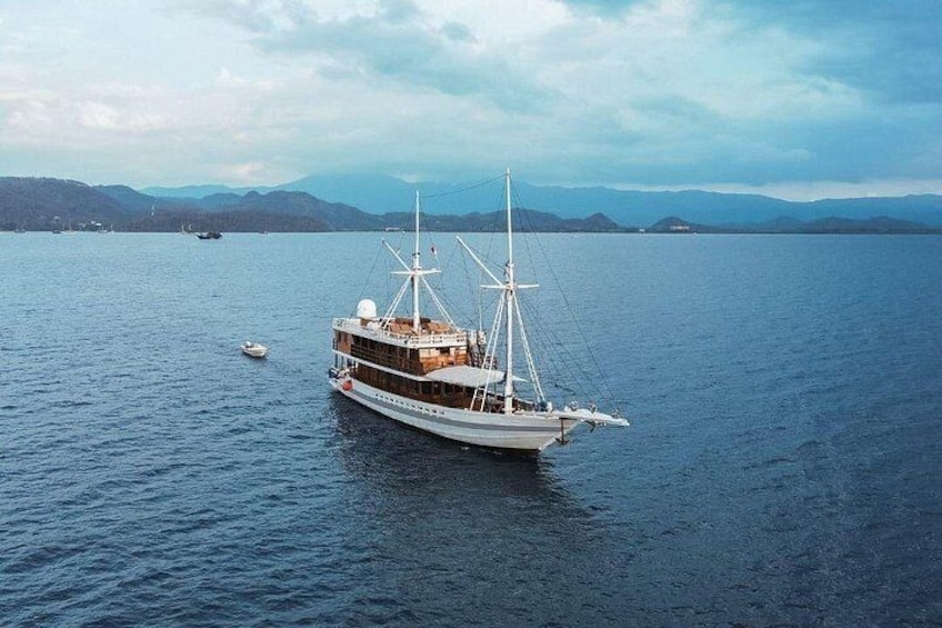Ein großes Segelschiff auf ruhigem Wasser vor einer gebirgigen Kulisse. 1