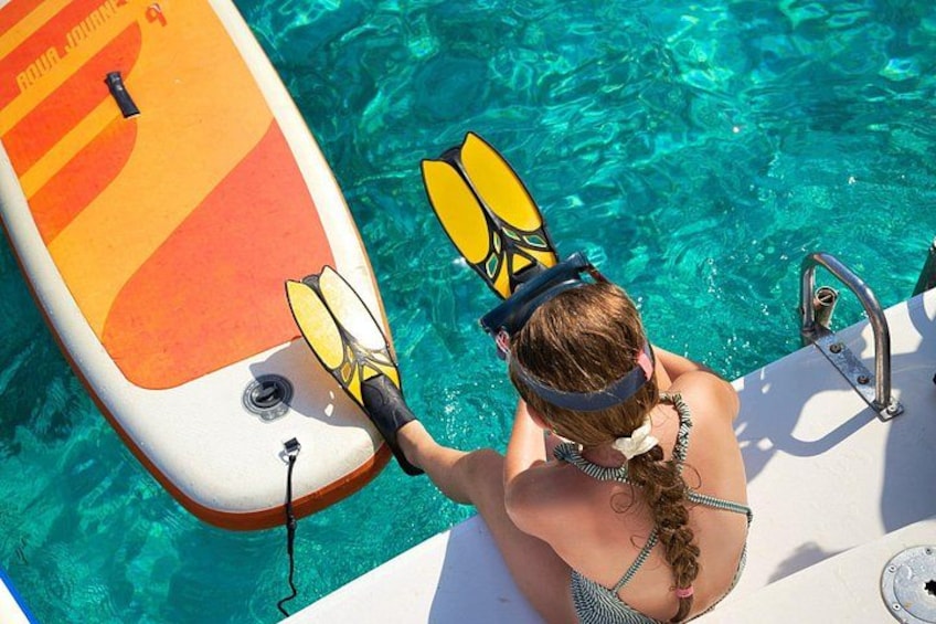 A person in a bikini with a snorkel and fins, holding a paddleboard in a pool. 3