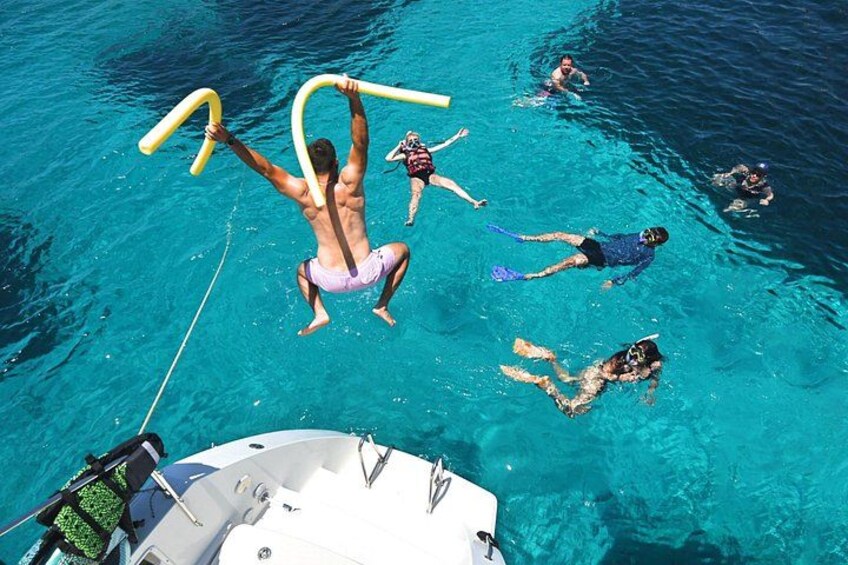 People swimming in a clear blue pool with a boat in the foreground. 4