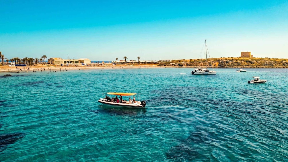 A coastal scene with boats on the water, a sandy beach, and a hill with ruins. 5