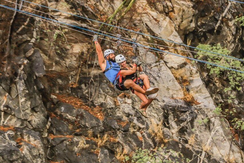 Two people rappelling down a rocky cliff. 3