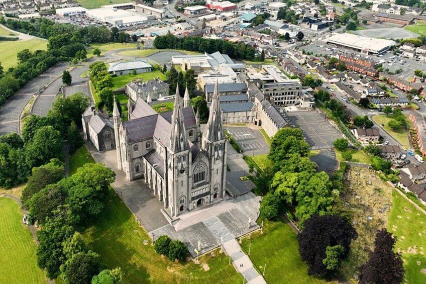A large church with a prominent spire, surrounded by green spaces and a parking lot. 3