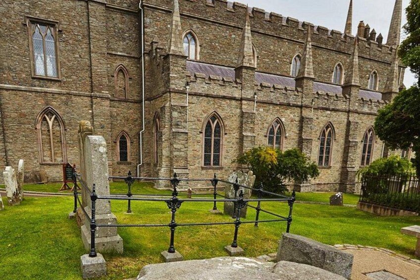 A historic stone building with arched windows and a grassy courtyard. 2