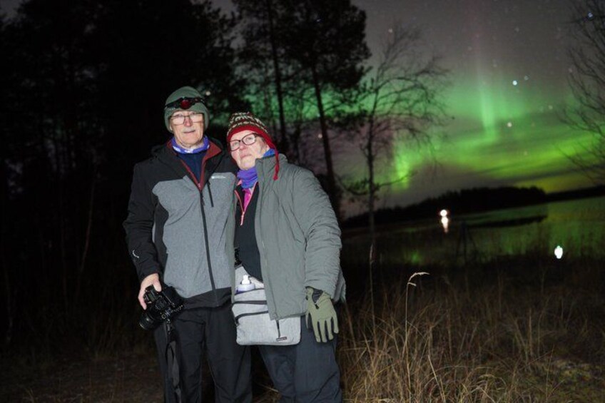 Two people standing outdoors at night with the aurora borealis in the background. 5
