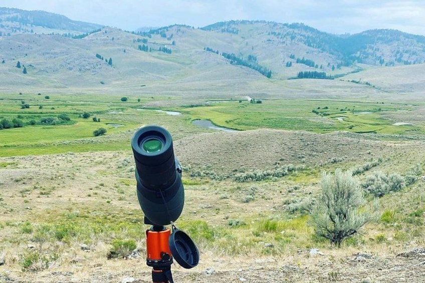 A landscape with a telescope, a small pond, and rolling hills in the background. 5