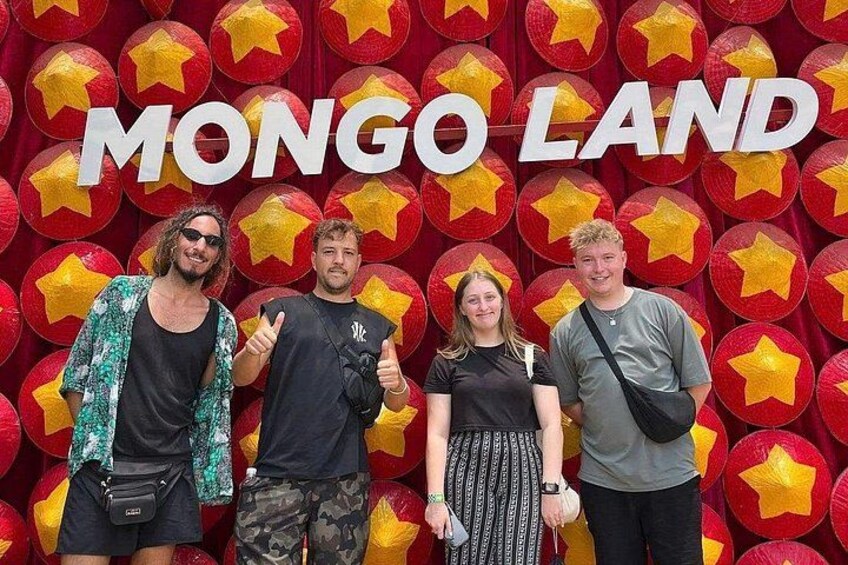 Four people standing in front of a backdrop with the text 'MONGO LAND' and star decorations. 2