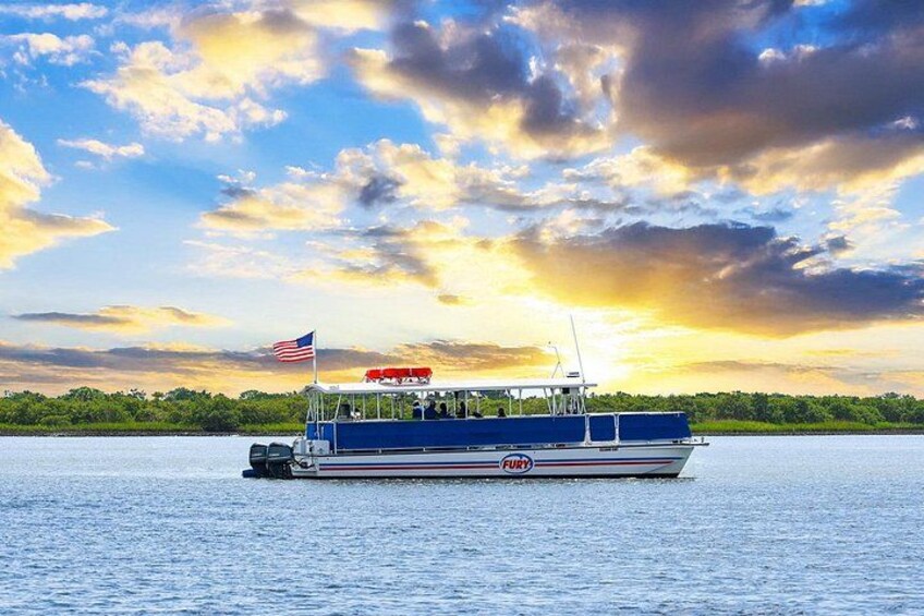 Een boot met een Amerikaanse vlag, die over kalm water vaart met een zonsondergang op de achtergrond. 2