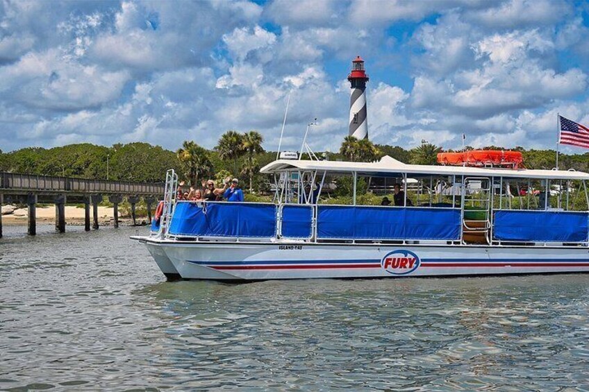 A boat with 'FURY' written on it, docked near a lighthouse and a pier. 1