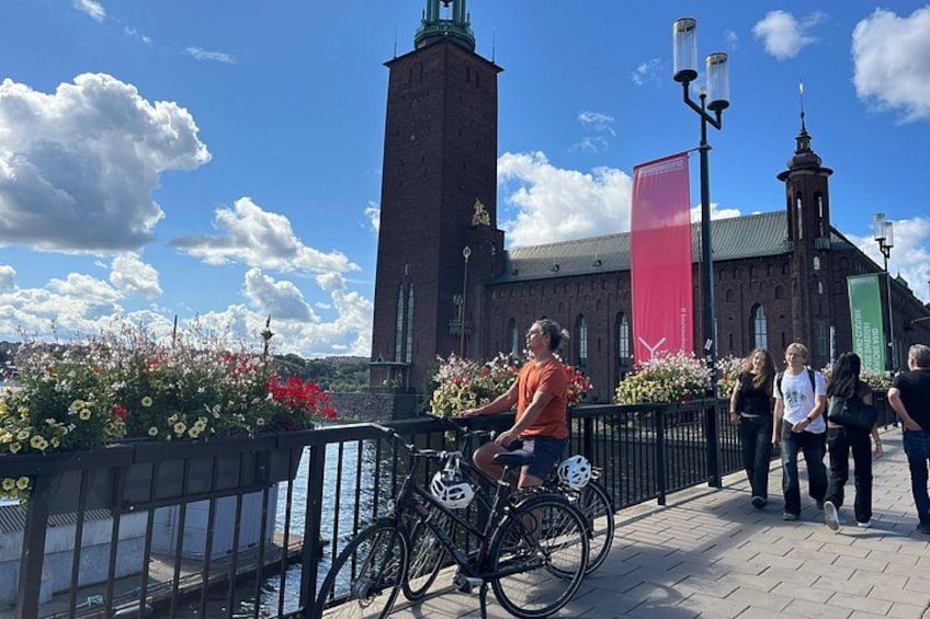 A historic building with a red banner, a cyclist, and a pedestrian walkway. 2