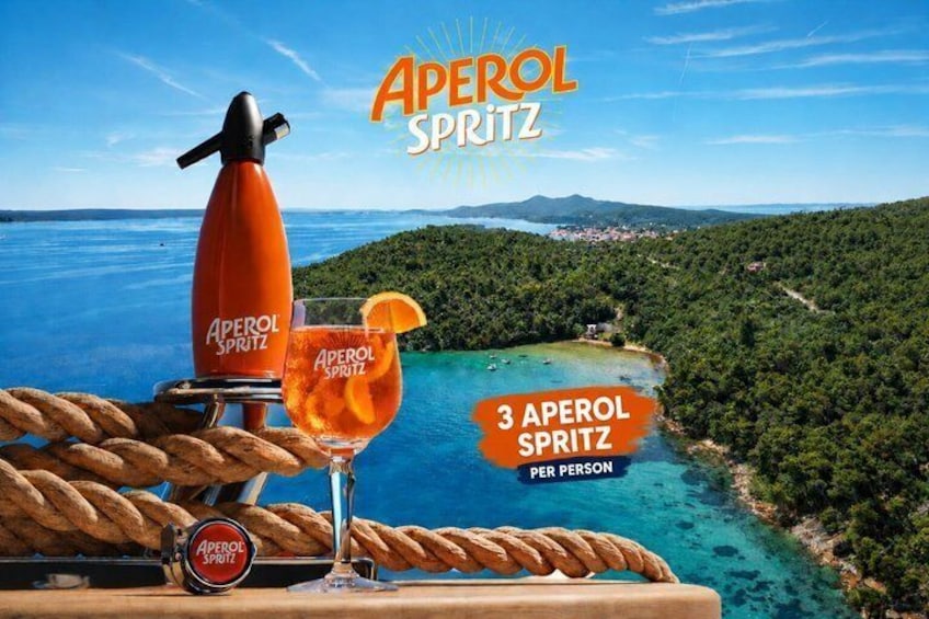 Ein malerischer Blick auf eine Küstenlandschaft mit einem Aperol Spritz und einem Glas auf einer Holztischplatte. 1