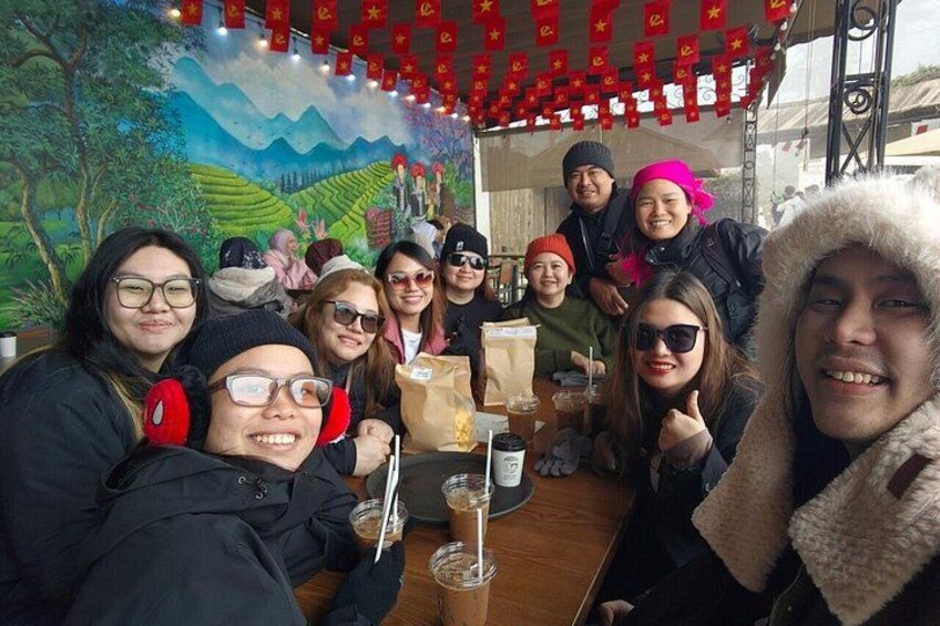 A group of people sitting at a table with drinks and a mural in the background. 4