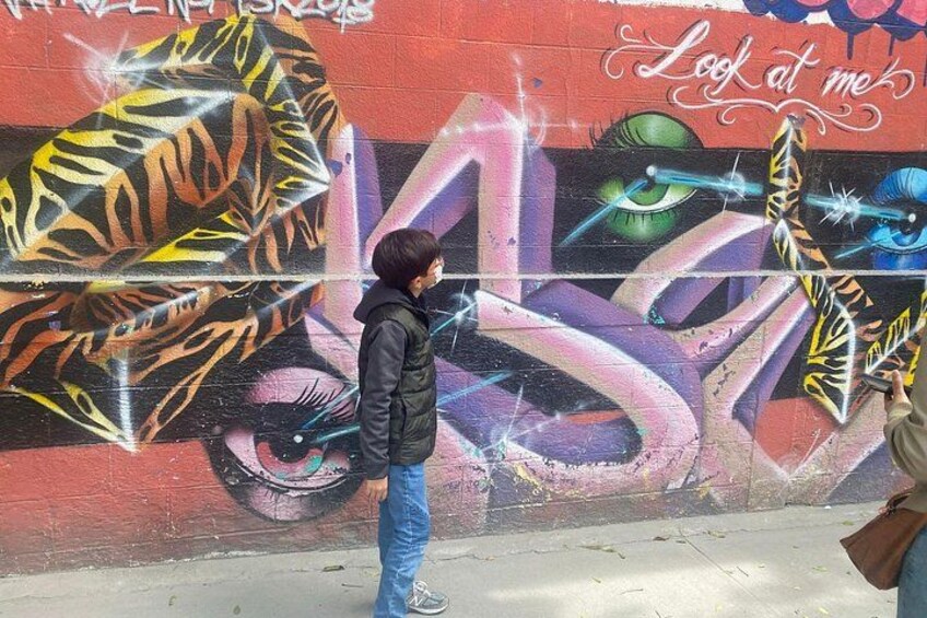 Une personne prend une photo d’une fresque murale colorée, réalisée à la bombe. 4